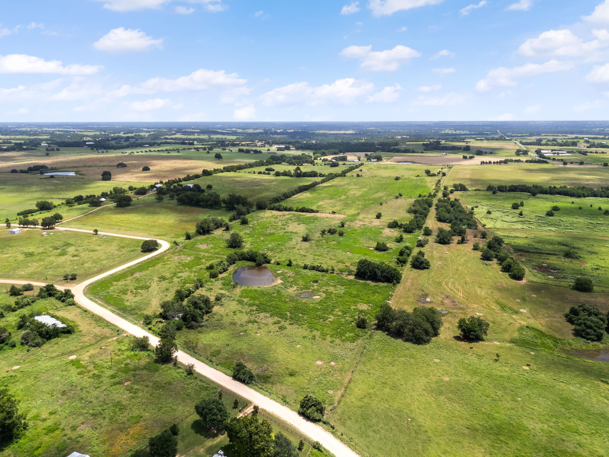 0 Thielemann Road Industry, TX 78944 - Photo 35 of 40 Vast green acreage featuring winding roads, scattered trees, and tranquil ponds under an open sky.