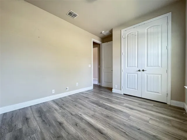 a view of an empty room with wooden floor and closet