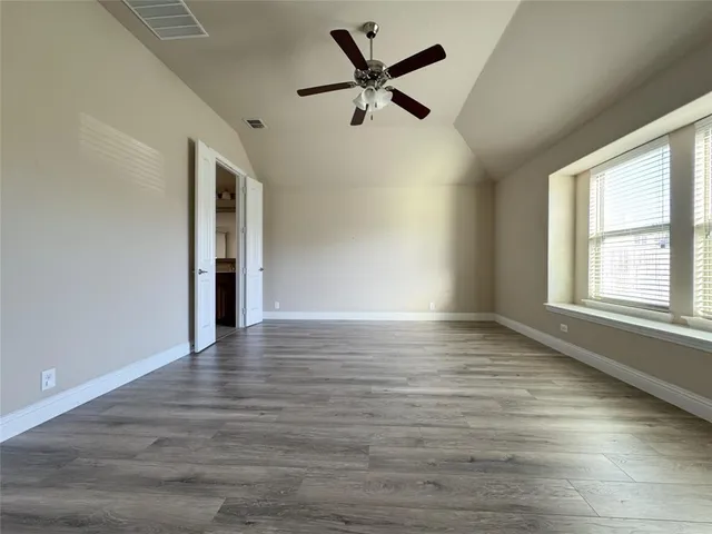 a view of an empty room with a fireplace and wooden floor