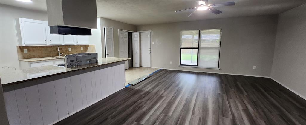 a kitchen with wooden floors and wide window