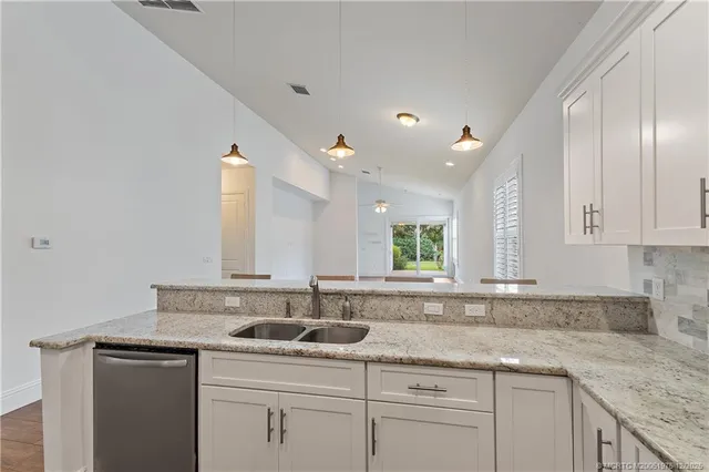 an empty room with chandelier fan and windows