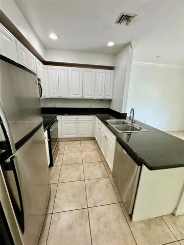 a kitchen with granite countertop a sink a stove top oven and cabinets