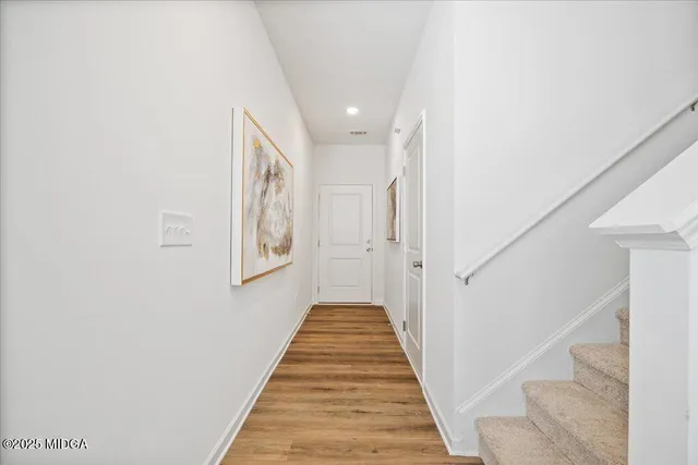 a view of a hallway with wooden floor and stairs