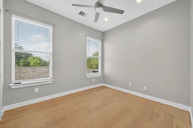 an empty room with a window and ceiling fan