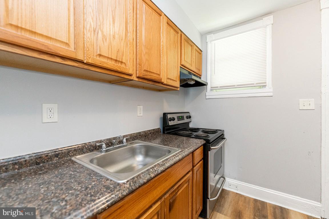 3006 Mathews Street Baltimore, MD 21218 - Photo 11 of 25 a kitchen with stainless steel appliances granite countertop a sink a cabinets and a wooden floor