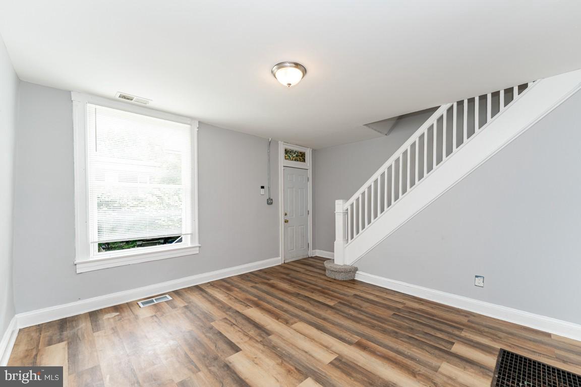 3006 Mathews Street Baltimore, MD 21218 - Photo 4 of 25 a view of an empty room with wooden floor and a window