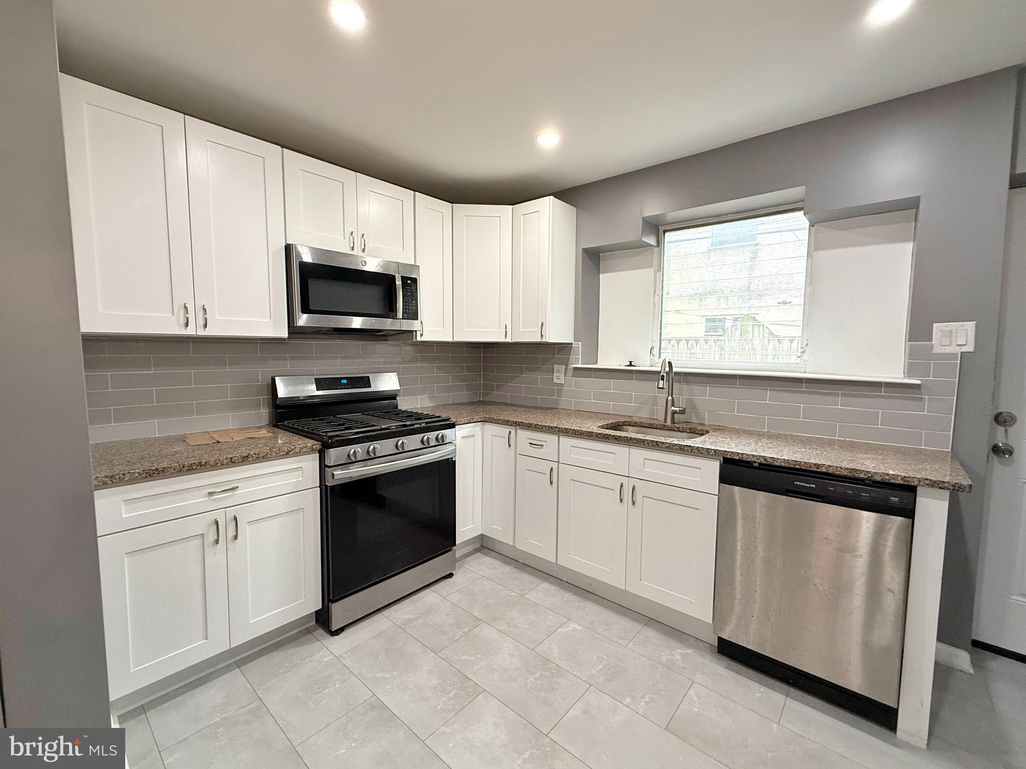1114 Mercy Street Philadelphia, PA 19148 - Photo 7 of 35 a kitchen with granite countertop white cabinets sink and stainless steel appliances
