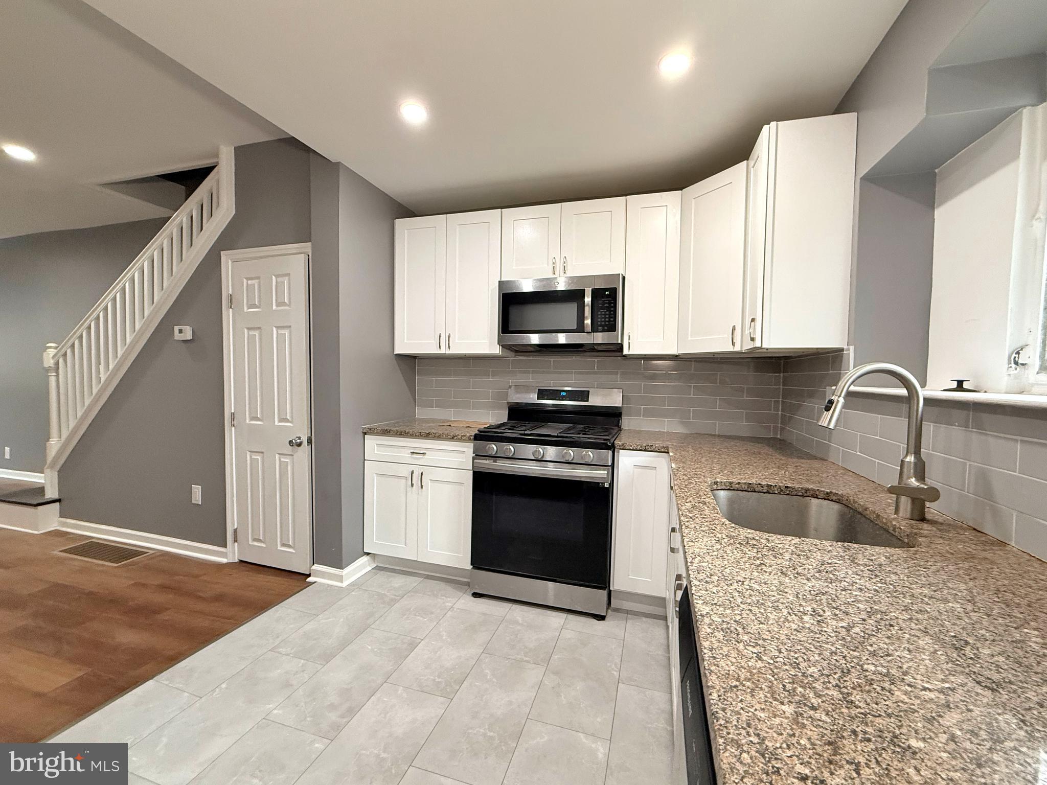 1114 Mercy Street Philadelphia, PA 19148 - Photo 8 of 35 a kitchen with stainless steel appliances granite countertop a sink and a stove top oven with wooden floor