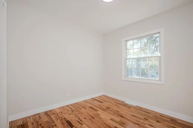 an empty room with wooden floor and a window