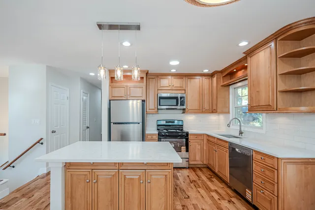 a kitchen with kitchen island granite countertop a sink a counter top space stainless steel appliances and cabinets