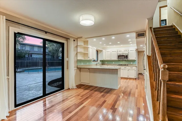 a large white kitchen with granite countertop a stove top oven a sink and dishwasher with wooden floor