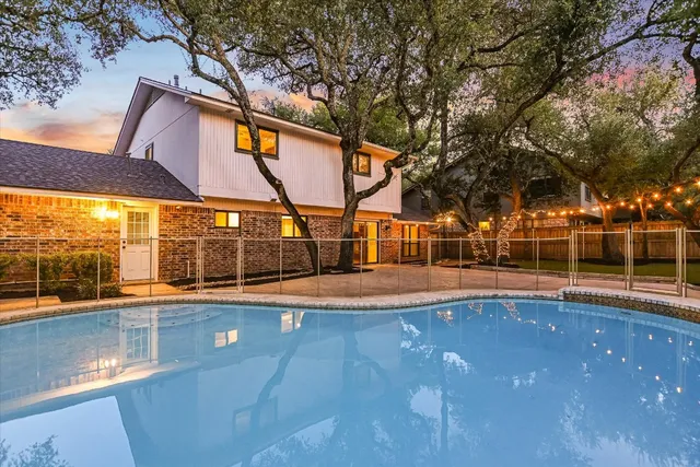 a view of a swimming pool with a bench and trees in the background
