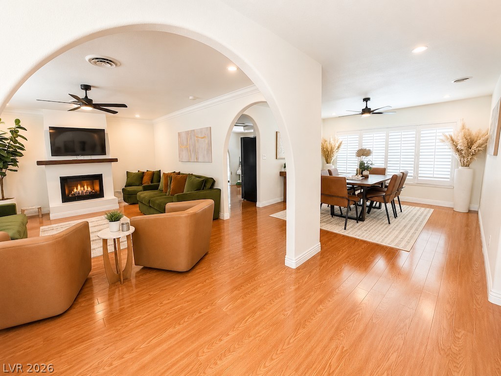 3010 East Viking Road Las Vegas, NV 89121 - Photo 8 of 48 Archways connect a vibrant living room, showcasing a fireplace and hardwood floors, to an inviting dining area.