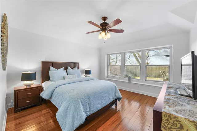 a bedroom with a bed a large window with wooden floor