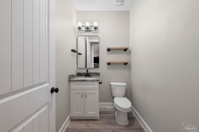 a bathroom with a granite countertop sink a toilet a mirror and shower