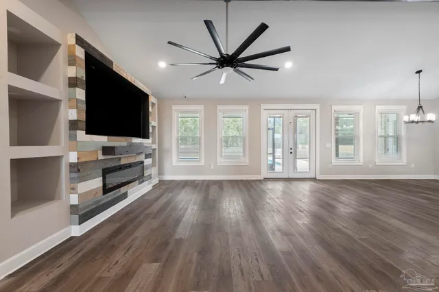 a view of a room with wooden floor a ceiling fan and windows