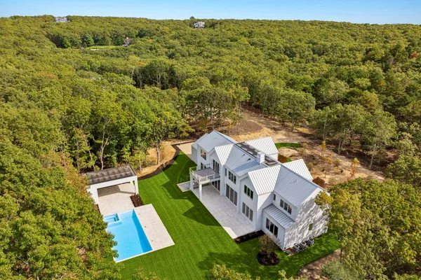 an aerial view of residential house with outdoor space and trees all around