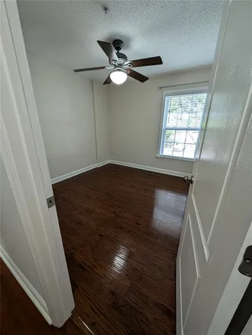 a view of an empty room with wooden floor and windows