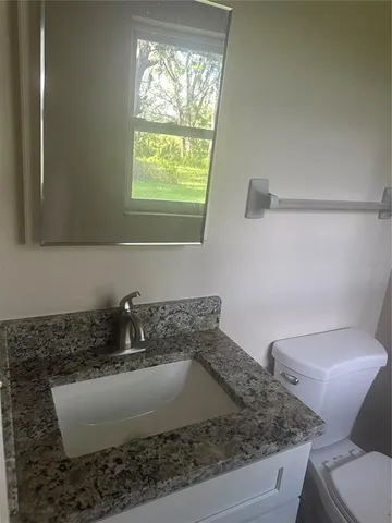 a bathroom with a granite countertop sink and a toilet