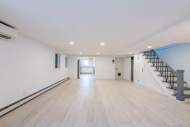 a view of an empty room with wooden floor and stairs