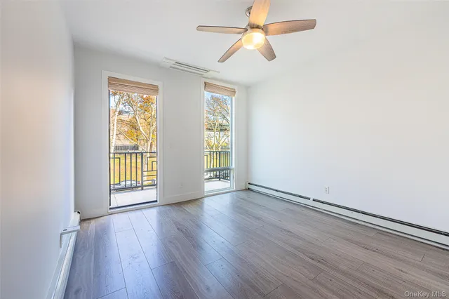 an empty room with wooden floor fan and windows