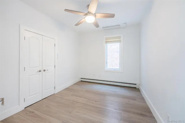 an empty room with wooden floor ceiling fan and windows