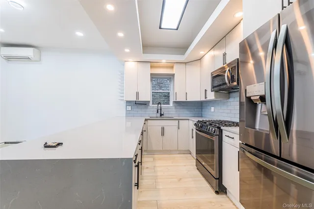 a kitchen with stainless steel appliances granite countertop a refrigerator a stove and a sink with wooden floor