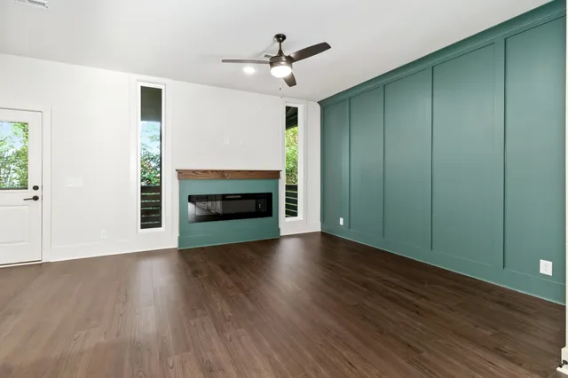 an empty room with wooden floor a fireplace and windows