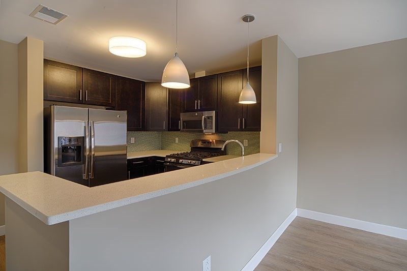 33 Rogers Street, Unit 421 Cambridge, MA 02142 - Photo 2 of 7 a large kitchen with a large counter top stainless steel appliances and cabinets