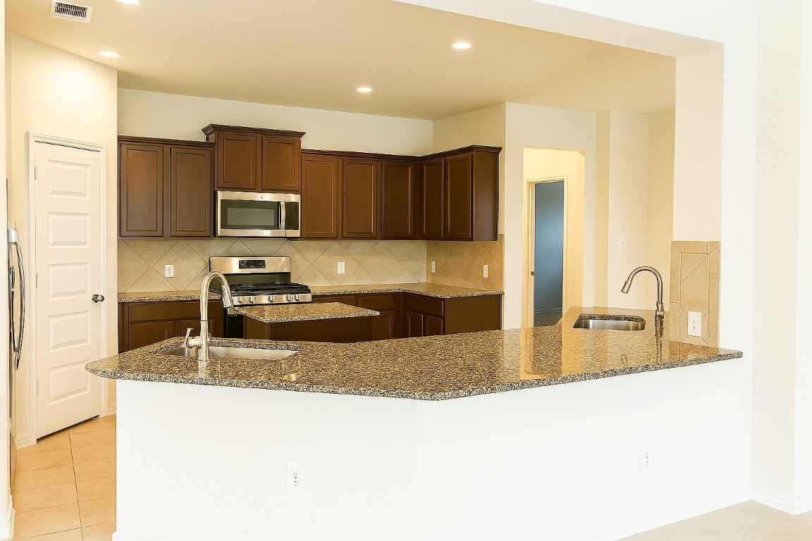 208 Durata Drive San Marcos, TX 78666 - Photo 13 of 25 Kitchen featuring dark stone counters, decorative backsplash, light tile patterned flooring, and recessed lighting