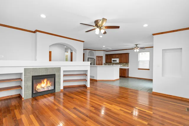 a view of a livingroom with a fireplace a ceiling fan and kitchen view