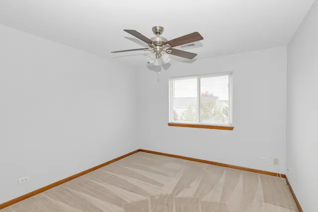 an empty room with a window and a ceiling fan