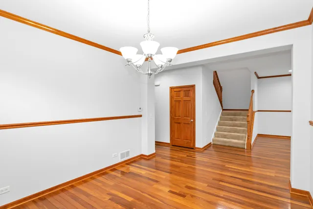 a view of an empty room with wooden floor and stairs