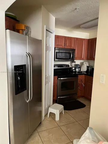 a kitchen with stainless steel appliances kitchen island granite countertop a refrigerator and a sink