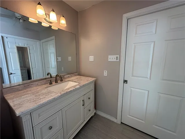 a bathroom with a granite countertop sink a light fixture and a mirror