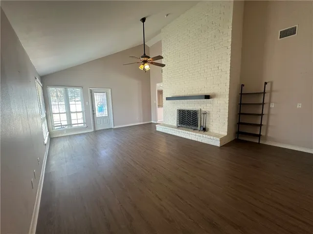 an empty room with wooden floor fireplace and windows