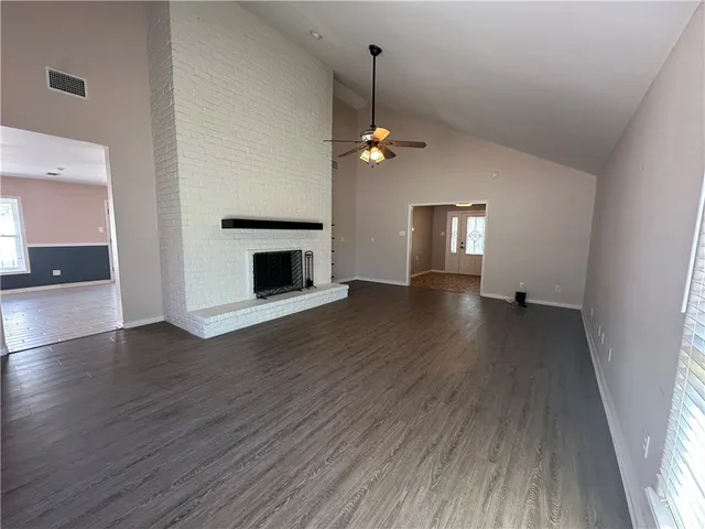 an empty room with wooden floor fireplace and windows