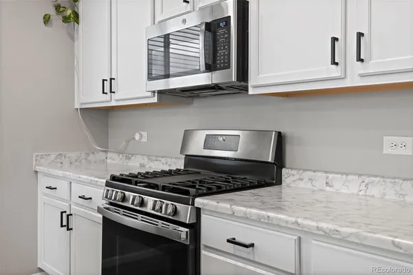 a kitchen with granite countertop white cabinets and stainless steel appliances