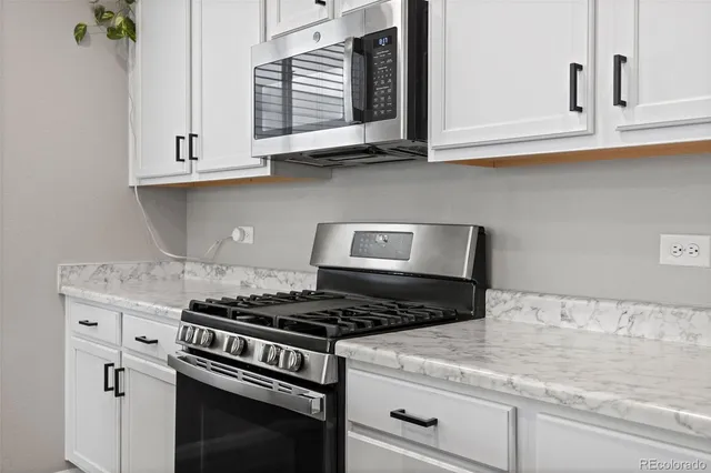 a kitchen with granite countertop white cabinets and stainless steel appliances