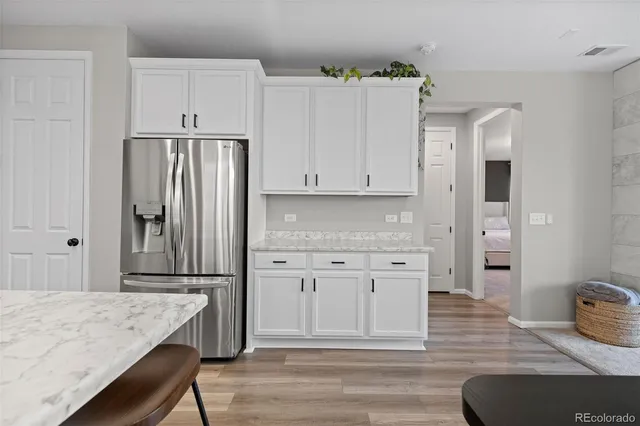 a kitchen with granite countertop white cabinets and refrigerator