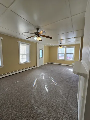a view of a livingroom with a chandelier fan and windows