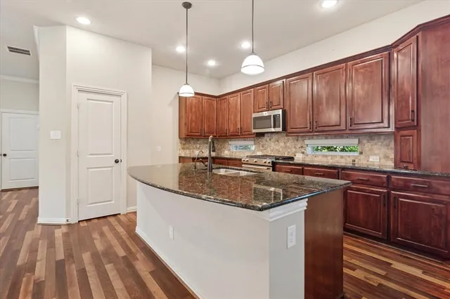 a kitchen with kitchen island granite countertop a sink a counter top space appliances and cabinets