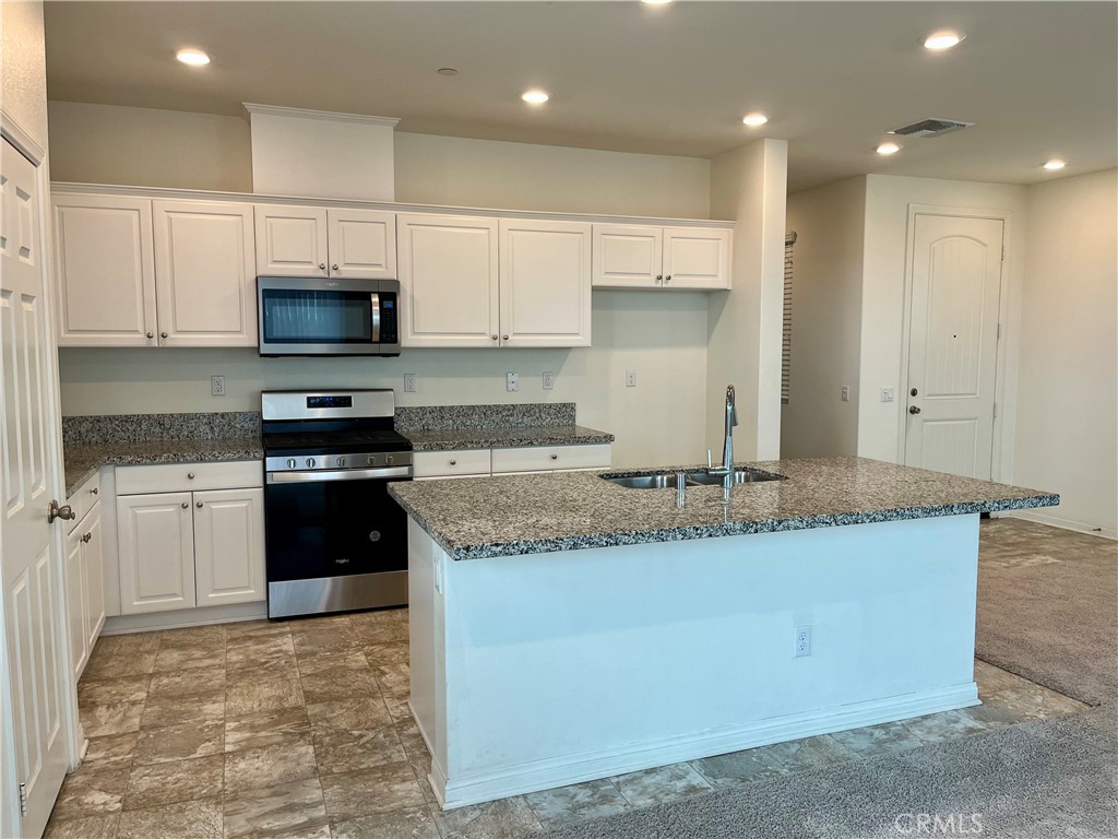 1586 Redwoods Drive Place Upland, CA 91784 - Photo 3 of 18 a kitchen with kitchen island granite countertop a sink a counter top space stainless steel appliances and cabinets