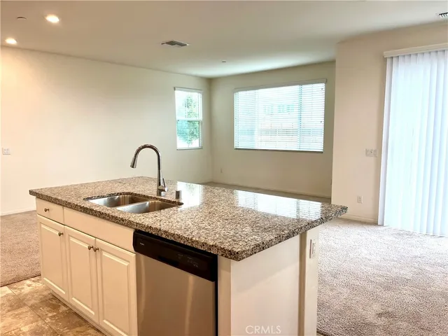 a kitchen with kitchen island granite countertop a sink and white cabinets