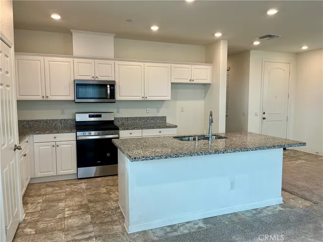 a kitchen with kitchen island granite countertop a sink a counter top space stainless steel appliances and cabinets