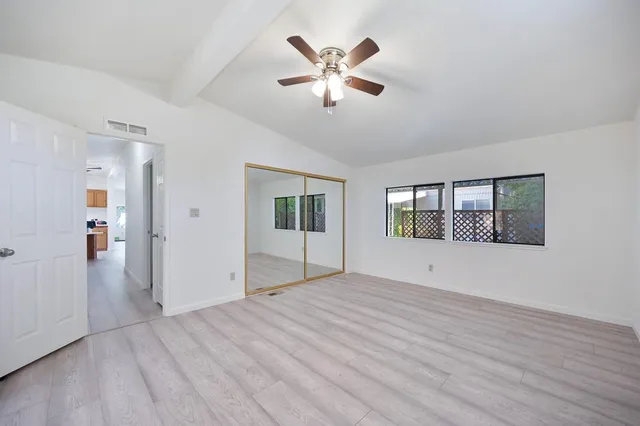 a view of an empty room with window and wooden floor