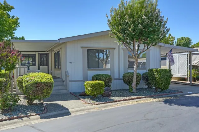 a front view of a house with garden and plants
