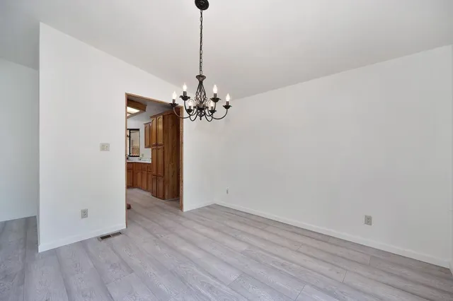 a view of a chandelier in big room and wooden floor