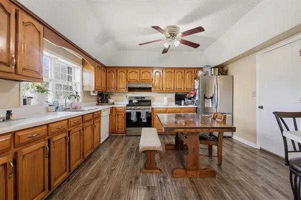 a kitchen with stainless steel appliances kitchen island granite countertop wooden floors a stove a sink a dining table and chairs