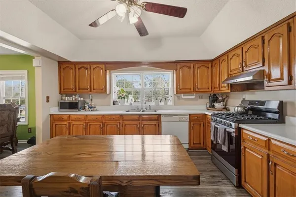 a large kitchen with stainless steel appliances granite countertop wooden cabinets a stove a sink a dining table and chairs
